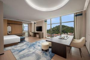 珠海市にあるDays Hotel by Wyndham Zhuhai Jinwanのベッドと机と大きな窓のある寝室