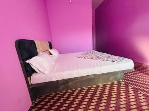 a small bed in a room with a pink wall at Hotel Sanwariya in Degāna