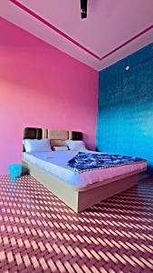 a bedroom with a bed with pink and blue walls at Hotel Sanwariya in Degāna