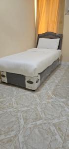a bed sitting in a bedroom with a tiled floor at هومي in Salalah