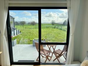 a room with a view of a field through a window at The Mann Homestay, Premium King Room with Private Ensuite, Near Waihi & Coromandel in Waihi