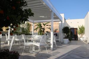 a group of white chairs and tables on a patio at Nesea Bed and Breakfast in San Vito lo Capo