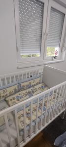 a white crib in a room with two windows at Apartman N&L in Sombor +63 photos