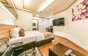 a hotel room with a bed and a tv at H Hotel in Ulsan