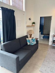 a blue couch in a living room with a window at Rangiputa Retreat in Karikari Peninsula