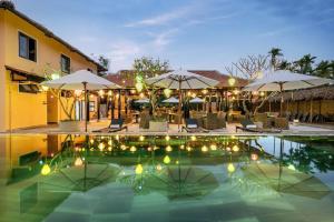 a resort with a pool with umbrellas and chairs at Zen B Hoian Villa in Cam Thanh