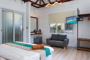 a bedroom with a bed and a chair and a television at Quicksand Rasdhoo in Rasdhoo