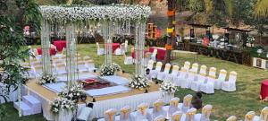 an outdoor wedding with white tables and chairs at Blue horiizon valley retreat in Khed