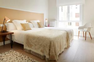 1 dormitorio con 1 cama grande con manta blanca en Zabaleta Beach by FeelFree Rentals, en San Sebastián