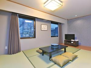 ein Wohnzimmer mit Tisch und Fernseher in der Unterkunft Hotel Keifuku Fukui Ekimae in Fukui