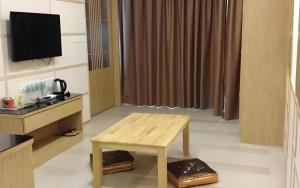 a living room with a table and a television at LF Hotel Tapah in Kampar