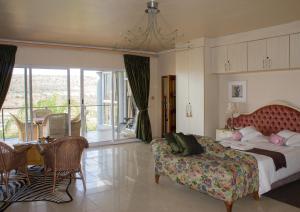 a bedroom with a bed and a couch and a table at Villa-Candilabra Guesthouse in Komatipoort