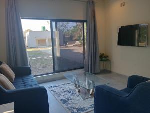 a living room with a glass table and blue chairs at Cosy One bedroom with good Solar backup & Wi-Fi in Lusaka