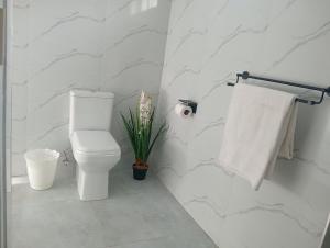 a white bathroom with a toilet and a towel at Cosy One bedroom with good Solar backup & Wi-Fi in Lusaka +17 photos