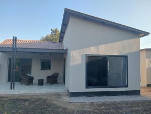 a house with two chairs and a large window at Cosy One bedroom with good Solar backup & Wi-Fi in Lusaka