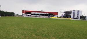 a large building with a green field in front of it at Hotel O Sangam Gardan in Sipra