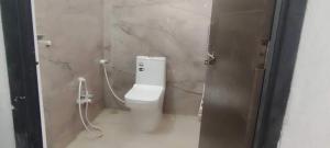 a bathroom with a white toilet in a stall at Hotel O Sangam Gardan in Sipra +1 photo