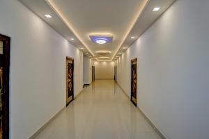 a long corridor with white walls and a ceiling with a light at Spot On THE RAJA GRAND in Akbarpur +21 photos