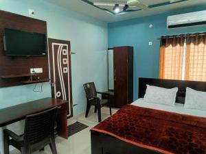 a bedroom with a bed and a desk and a television at Hotel O Shrihaan Residency in Rāmachandrapuram