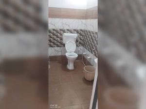 a bathroom with a toilet and a bucket at SPOT ON New Phulpur Restaurant And Hotel in Phūlpur