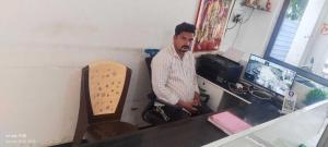 a man sitting at a desk in front of a computer at SPOT ON New Phulpur Restaurant And Hotel in Phūlpur