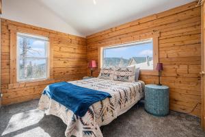 una camera da letto con pareti in legno, un letto e una finestra di Cozy Mountain Cabin in Idaho Springs a Saint Marys