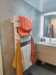 ein Badezimmer mit Handtüchern, einem Waschbecken und einem Spiegel in der Unterkunft Deauville Proche Plage - Piscine Chauffée - Jacuzzi - Sauna in Deauville