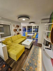 Una sala de estar con un sofá amarillo y una mesa. en Apartman ALEK Stupine ,Tuzla, en Tuzla