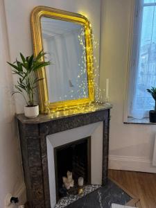 a gold mirror over a fireplace in a living room at La suite de la pépinière in Nancy