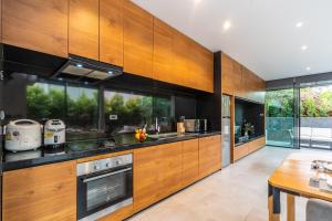 a large kitchen with wooden cabinets and a table at Sparrow Villa - Kamala Beach in Kamala Beach