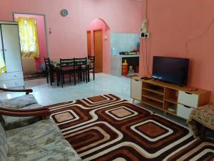 a living room with a couch and a television and a table at Homestay kak nun in Kampong Ru Sepuloh