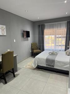 Un dormitorio con una cama y un escritorio y una ventana. en GlowtiAirbnb, en Centurion