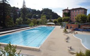 a large swimming pool with chairs and a building at T2 proche Thermes Vals Idéal curistes et familles in Vals-les-Bains
