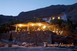 a building with lights on top of a stone wall at Taverna Akrogiali in Loutro