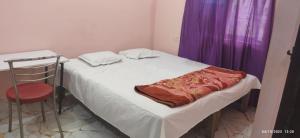 a small bed in a room with a purple curtain at Moon house in Bodh Gaya