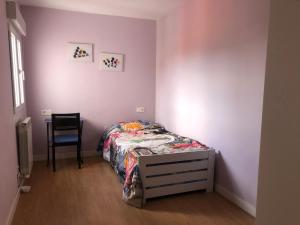 Un pequeño dormitorio con una cama y una silla. en Apartamento en Avenida Quevedo, en León