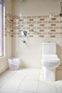 a white bathroom with a toilet and a shower at La Hostelgia in Manāli