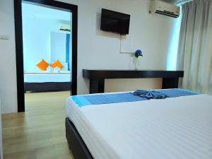 a hotel room with a bed and a television at The Regizt Jomtien Pattaya in Jomtien Beach