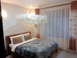 a bedroom with a bed and a chandelier at Zuri apartment in Lwero