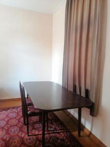 a table and a chair in a room with a curtain at Qokhna Samarqand in Samarkand