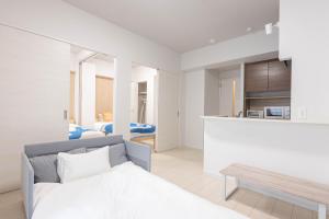 a white bedroom with a bed and a kitchen at Ekimae apartment in Hakata