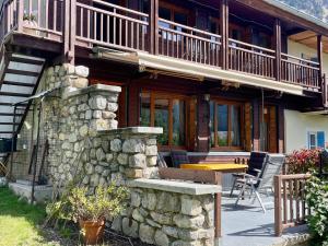 a house with a stone wall and a balcony at Bed and Breakfast Les Airelles in Val-des-Prés
