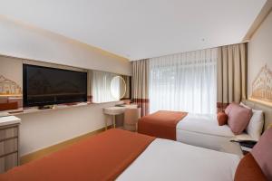 a hotel room with two beds and a flat screen tv at Ducale Lara - Ultra All Inclusive in Lara