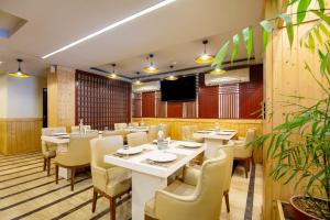a restaurant with tables and chairs and a flat screen tv at The Lohmod Premier Aerocity on NH-8 Mahipalpur Delhi Airport in New Delhi
