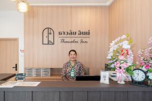 カタビーチにあるThawalai Inn Kataの売店のカウンターの後ろに立つ女