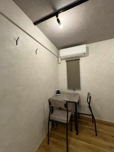 a table and chair in a room with a white wall at Simple Hotel Tenjin Fukuoka in Fukuoka