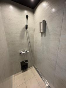 a bathroom with a shower with a phone on the wall at Simple Hotel Tenjin Fukuoka in Fukuoka +3 photos