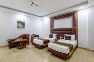 a hotel room with two beds and a chair at The Lohmod Premier Aerocity on NH-8 Mahipalpur Delhi Airport in New Delhi