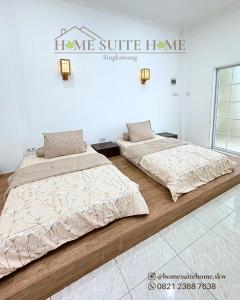 two beds in a room with a sign on the wall at Home Suite Home Singkawang in Singkawang