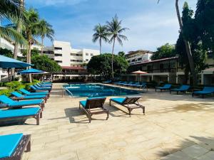 a swimming pool with blue lounge chairs and a resort at Nautical Inn in Pattaya Central